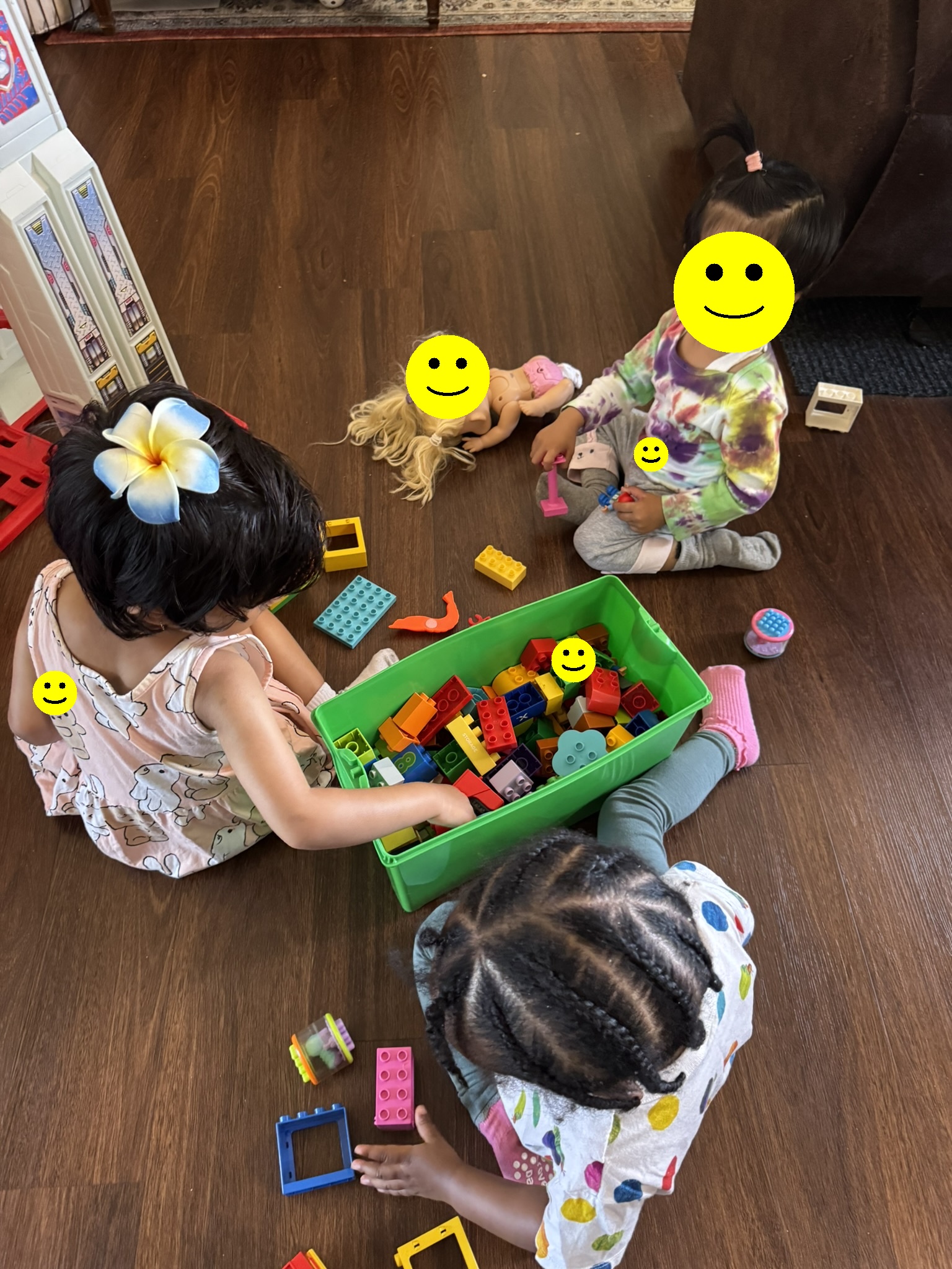 Three children sitting together on the floor building with DUPLO blocks